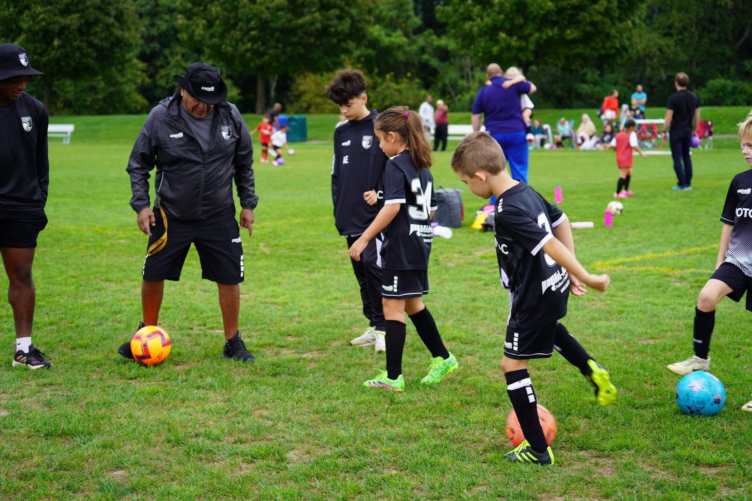 potomac soccer players boys and girls playing soccer on a field with their coach and soccer balls